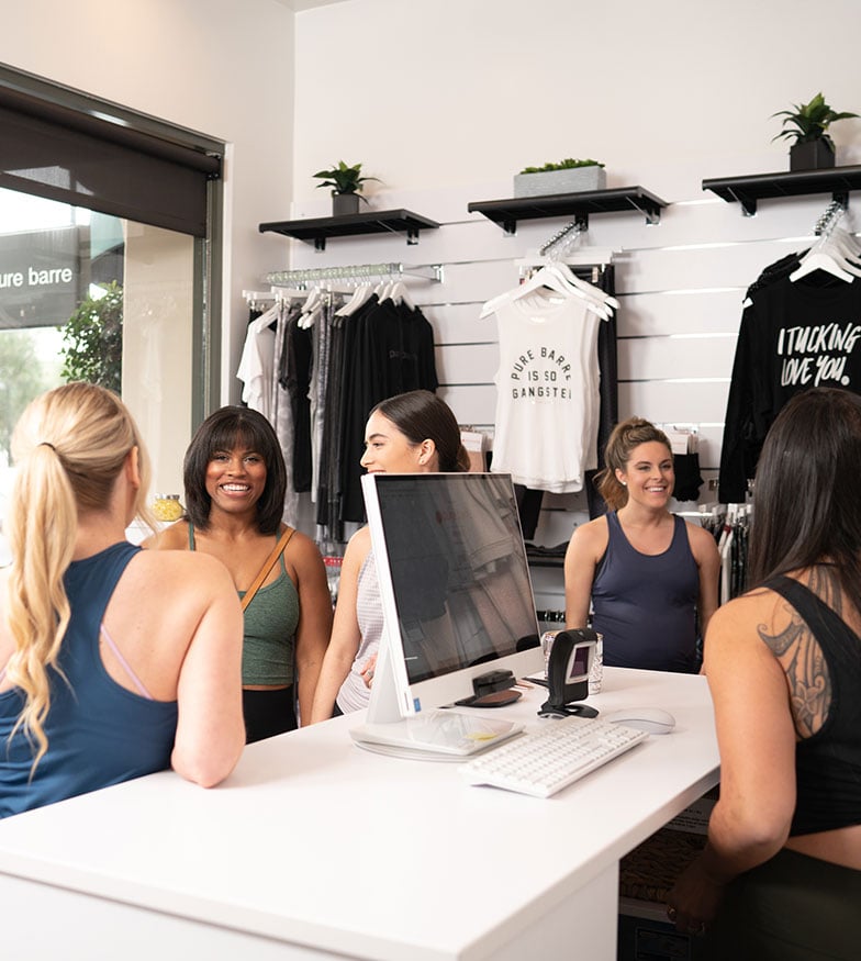 Group smiling next to front desk at Pure Barre