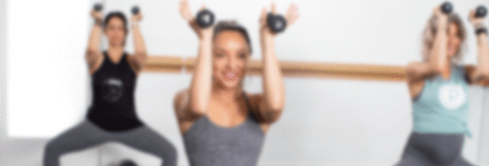 Three people squatting while holding dumbbells above their head