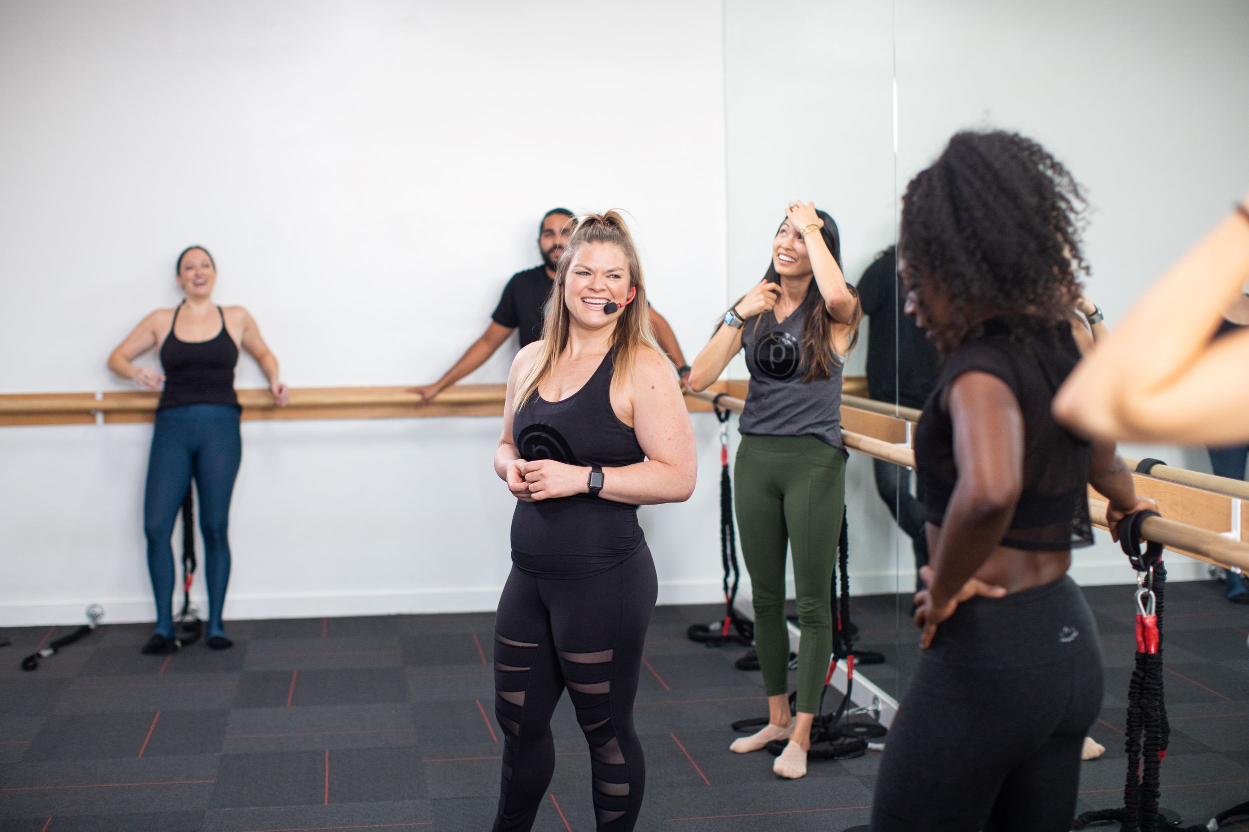 Pure Barre instructor smiling at group taking a break from workout